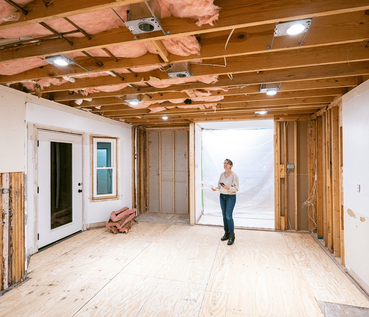 Woman inspecting unfinished room renovation progress.