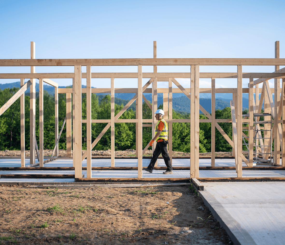 Construction worker walking through wooden framework.