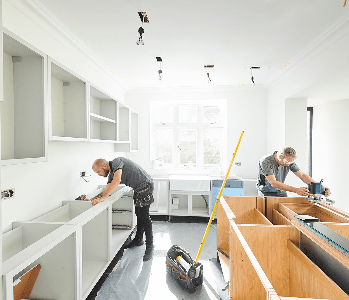 Two workers installing kitchen cabinets and counters.