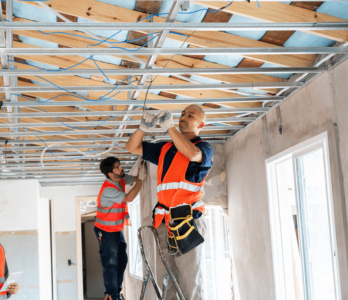 Workers installing ceiling in a building interior.